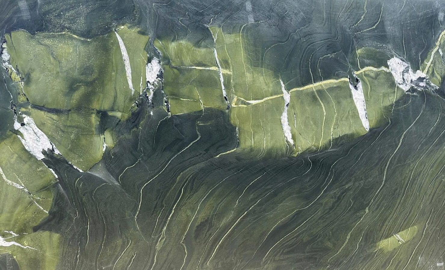 Canlı yeşil ve zeytin tonlarının bir araya geldiği bu mermer, üzerindeki beyaz ve koyu damarlarla doğadan ilham alan dinamik bir görünüm sunar. Özellikle iç mekan tasarımlarında doğal bir vurgu yapmak isteyenler için dikkat çekici bir seçimdir.